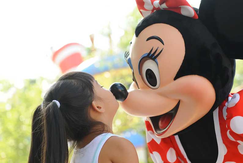Young child kissing Minnie Mouse on the nose at the Disneyland Resort on a trip booked by Main Street Magic, LLC., a no-fee travel agency specializing in Disney vacation planning | Authorized Disney Vacation Planner